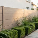 Clôture de jardin en composite avec texture bois dans un jardin résidentiel moderne aménagé avec des graminées et des pavés en pierre