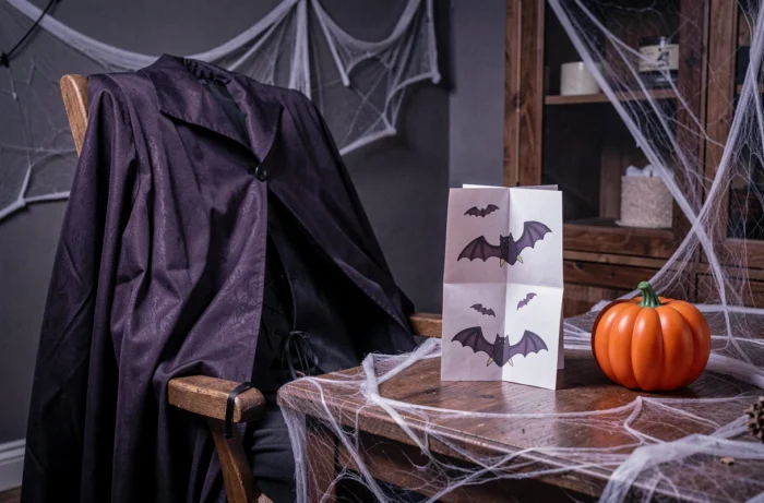 Costume de vampire posé près d'une cocotte en papier avec des dessins de chauve-souris